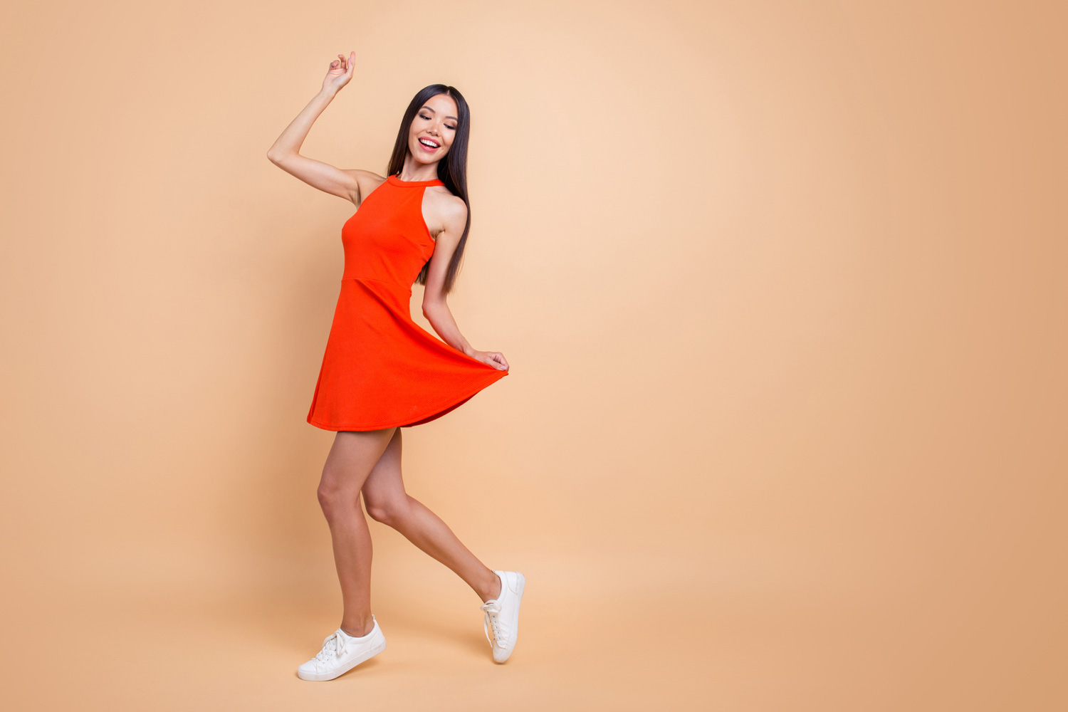 A young woman in an orange dress celebrating varicose veins recovery.